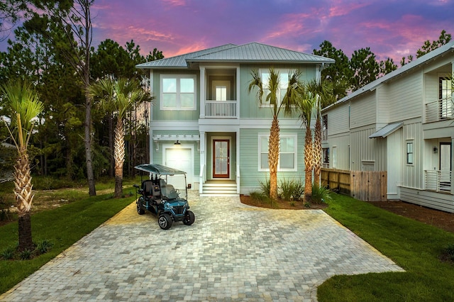 view of front facade featuring a garage, a yard, and a balcony