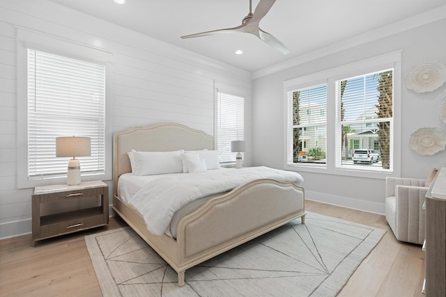 bedroom with ceiling fan, ornamental molding, wood walls, and light wood-type flooring