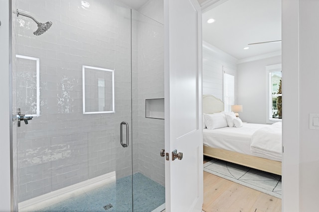 bathroom with wood-type flooring, a shower with door, and ornamental molding