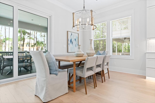 dining area with light wood-type flooring, crown molding, and an inviting chandelier