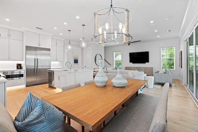 dining space with light hardwood / wood-style floors, an inviting chandelier, crown molding, and sink