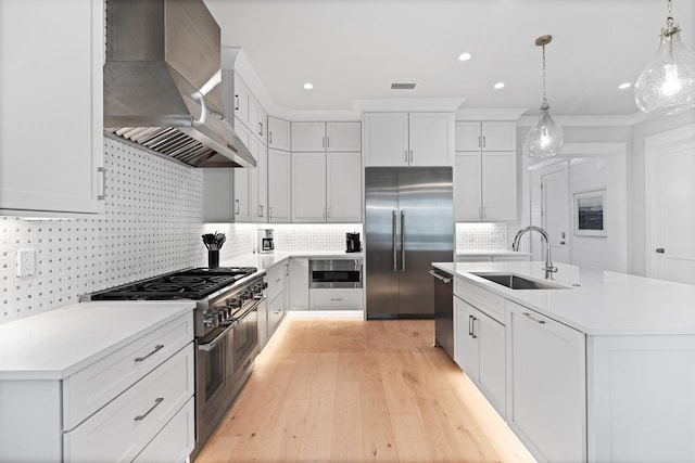 kitchen featuring sink, hanging light fixtures, wall chimney exhaust hood, tasteful backsplash, and premium appliances