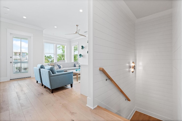 living room featuring plenty of natural light, ceiling fan, crown molding, and light hardwood / wood-style flooring