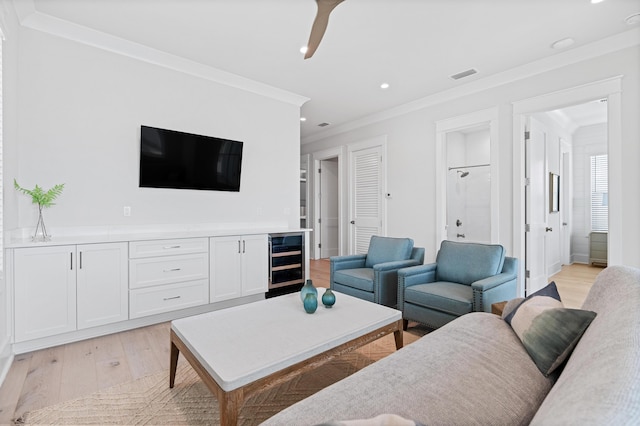 living room featuring crown molding, beverage cooler, and light hardwood / wood-style flooring