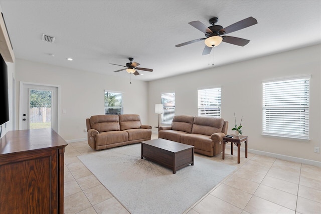 tiled living room with ceiling fan, a healthy amount of sunlight, and a textured ceiling