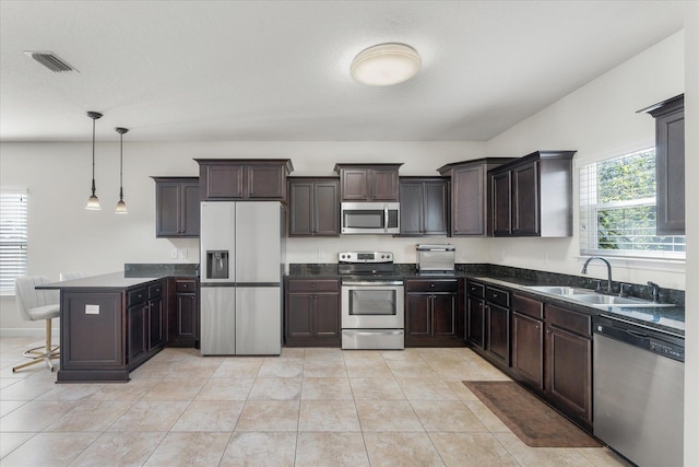 kitchen with stainless steel appliances, sink, pendant lighting, light tile patterned floors, and a breakfast bar area