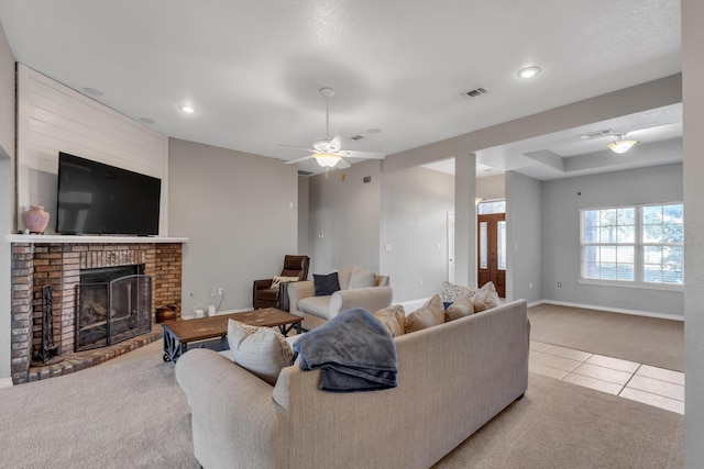 living room featuring light carpet, a fireplace, and ceiling fan