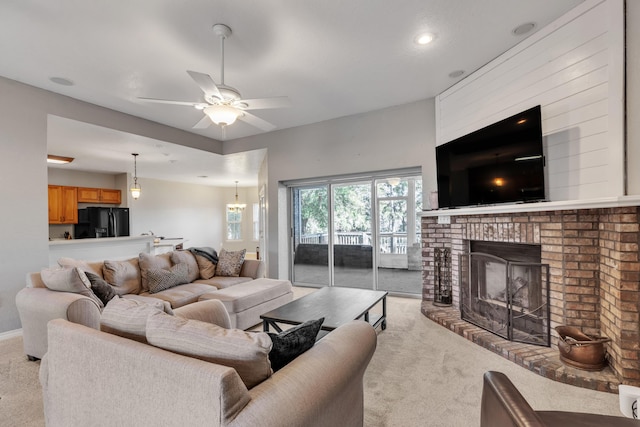 carpeted living room with ceiling fan and a brick fireplace