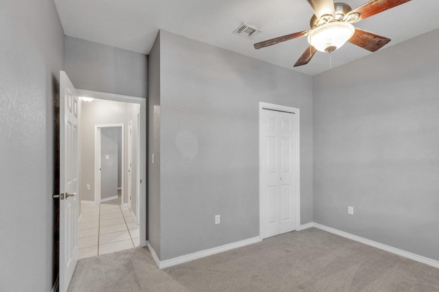 unfurnished bedroom featuring light carpet, a closet, and ceiling fan