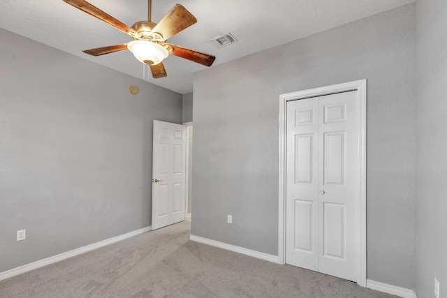 unfurnished bedroom with a closet, light colored carpet, and ceiling fan