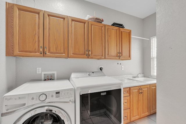 clothes washing area featuring cabinets, light tile patterned floors, sink, and washing machine and clothes dryer