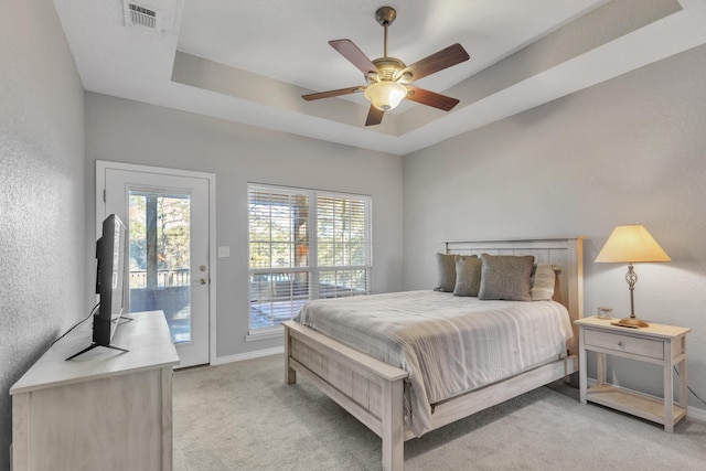 bedroom featuring access to exterior, light carpet, a raised ceiling, and ceiling fan