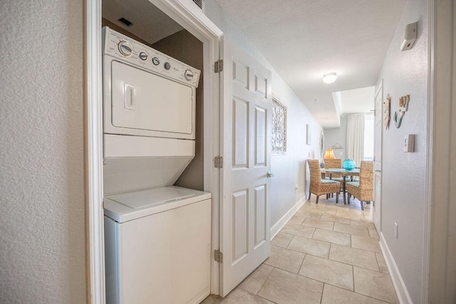 clothes washing area with light tile patterned floors and stacked washer / dryer