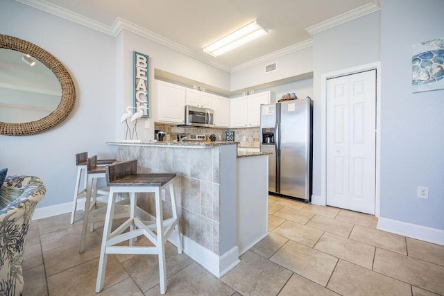 kitchen featuring stainless steel appliances, light stone counters, kitchen peninsula, a breakfast bar, and white cabinets