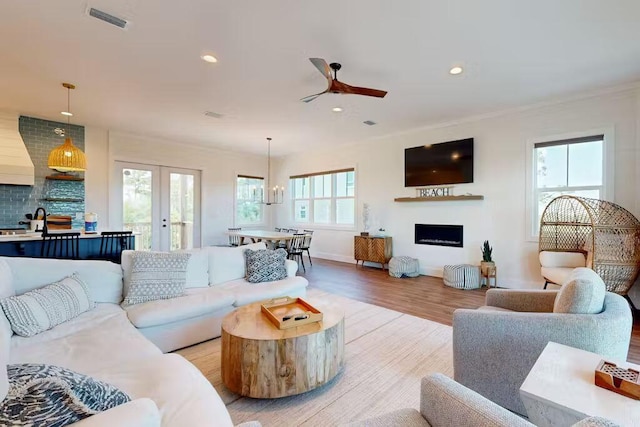 living room featuring ceiling fan with notable chandelier, light hardwood / wood-style floors, and a wealth of natural light