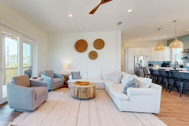 living room with ceiling fan, sink, and light hardwood / wood-style flooring