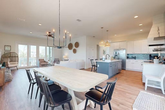 dining area featuring sink, a chandelier, and light wood-type flooring