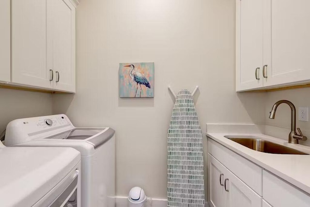 clothes washing area with washer and dryer, cabinets, and sink