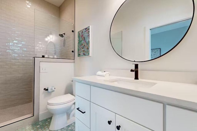 bathroom with tile patterned floors, vanity, toilet, and a tile shower