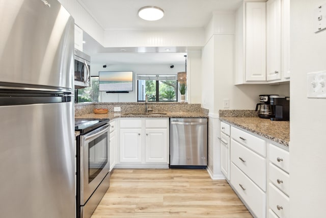 kitchen featuring appliances with stainless steel finishes, sink, stone counters, light hardwood / wood-style flooring, and white cabinets