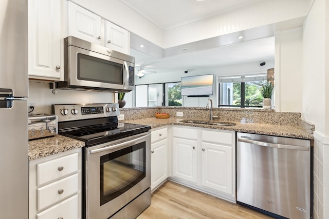 kitchen featuring appliances with stainless steel finishes, sink, light stone counters, and white cabinets