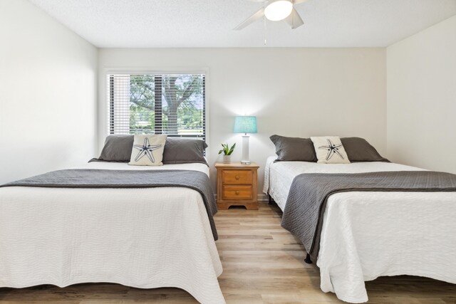 bedroom with a textured ceiling, ceiling fan, and light hardwood / wood-style floors