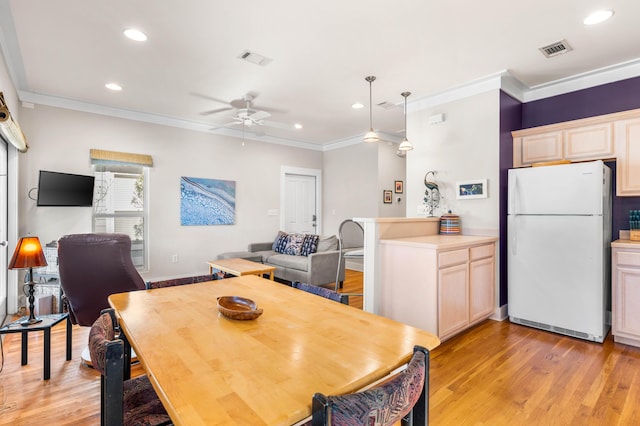 dining room featuring ceiling fan, light wood-type flooring, and crown molding