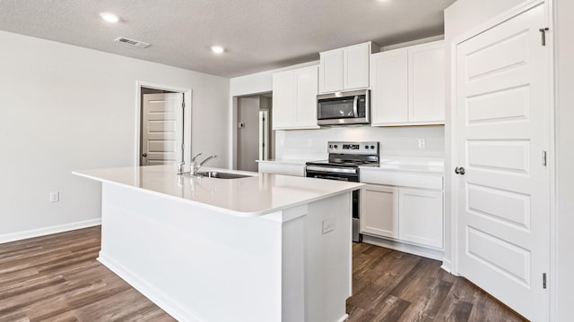 kitchen with an island with sink, appliances with stainless steel finishes, sink, and white cabinets