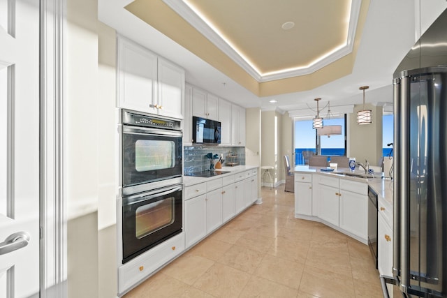 kitchen with a raised ceiling, backsplash, pendant lighting, white cabinets, and black appliances