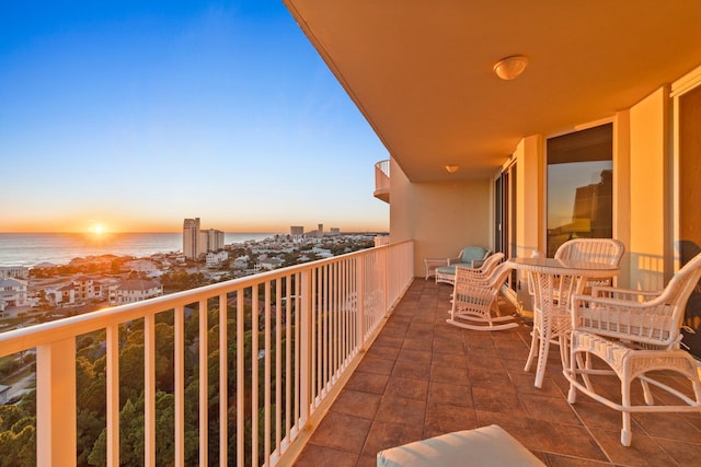 balcony at dusk featuring a water view