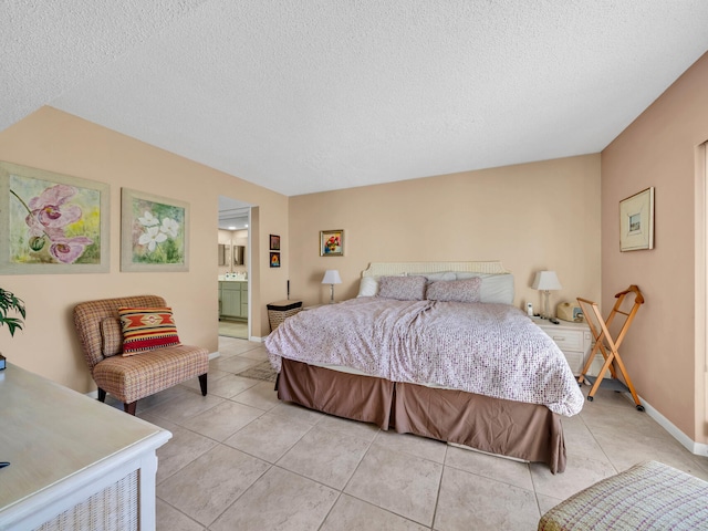 bedroom featuring ensuite bath, light tile patterned floors, and a textured ceiling