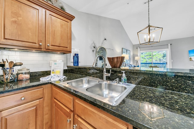 kitchen featuring decorative backsplash, vaulted ceiling, sink, an inviting chandelier, and hanging light fixtures