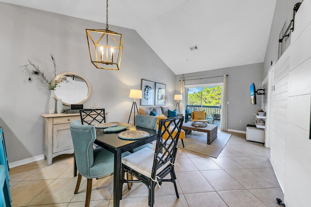 dining area with light tile patterned floors, high vaulted ceiling, and an inviting chandelier