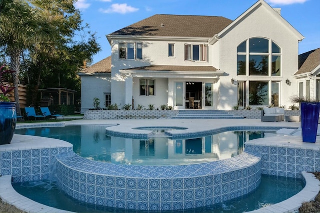 back of property with a swimming pool with hot tub