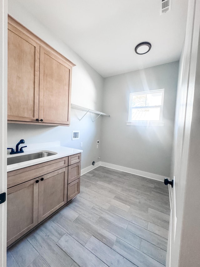 washroom with cabinets, hookup for a washing machine, electric dryer hookup, sink, and light hardwood / wood-style floors