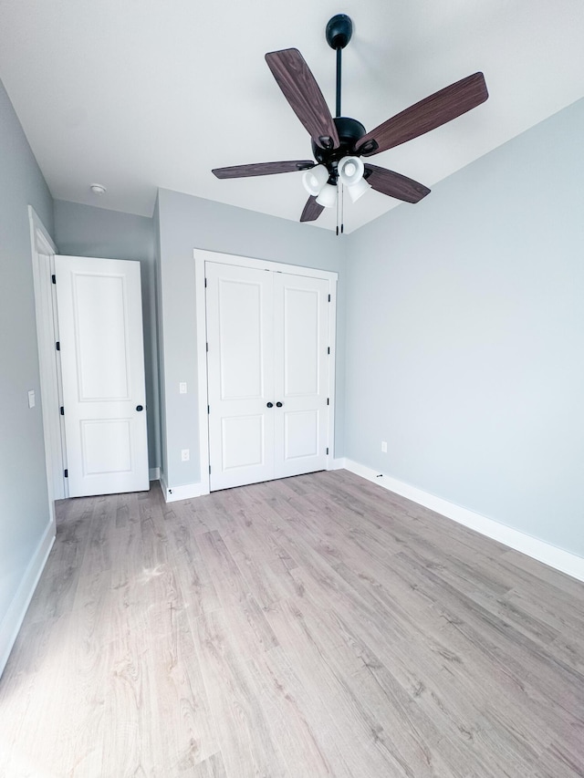 unfurnished bedroom with ceiling fan, a closet, and light wood-type flooring