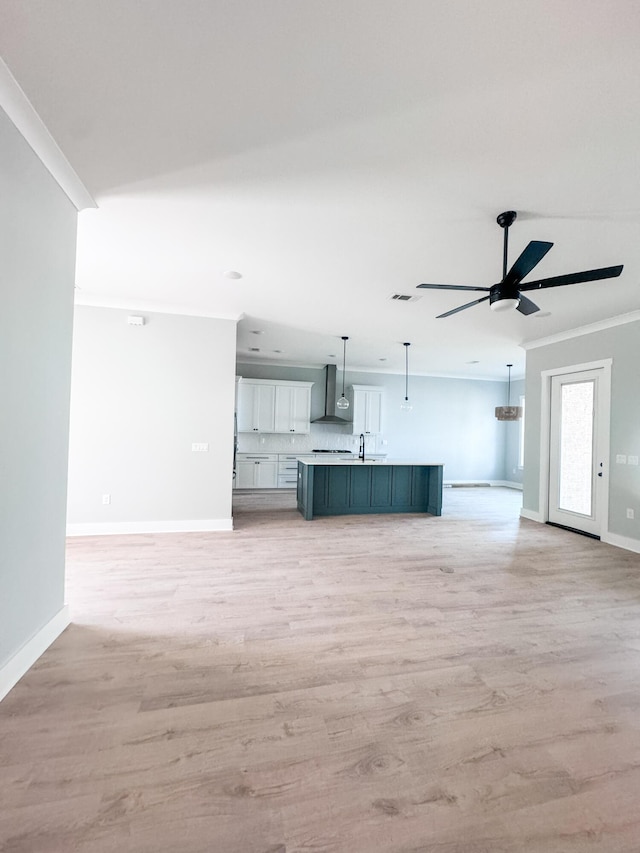 unfurnished living room featuring crown molding, sink, ceiling fan, and light hardwood / wood-style floors