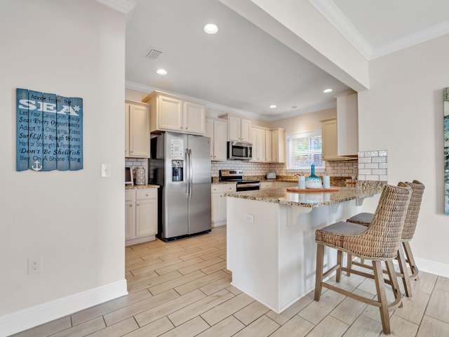 kitchen featuring light stone countertops, stainless steel appliances, kitchen peninsula, a breakfast bar, and light wood-type flooring