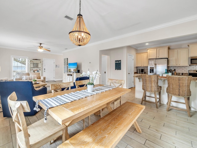 dining area featuring ceiling fan with notable chandelier, light wood-type flooring, and crown molding