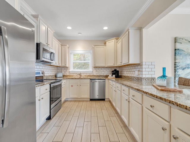 kitchen with tasteful backsplash, light stone counters, ornamental molding, stainless steel appliances, and cream cabinets