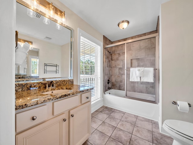 full bathroom with tile patterned flooring, vanity, bath / shower combo with glass door, and toilet