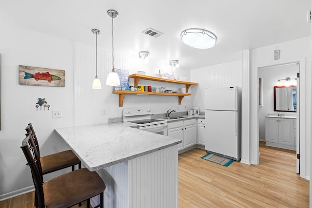 3799 E County Highway 30a # E-6, Santa Rosa Beach, FL 32459 - kitchen featuring white appliances, a peninsula, a breakfast bar, light wood-style floors, and open shelves