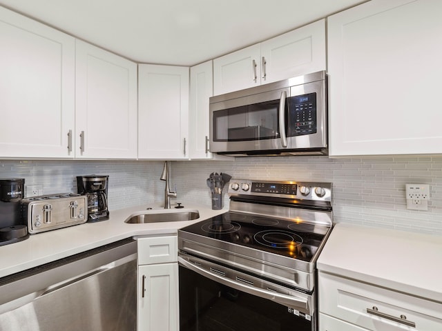 kitchen featuring white cabinets, sink, stainless steel appliances, and tasteful backsplash