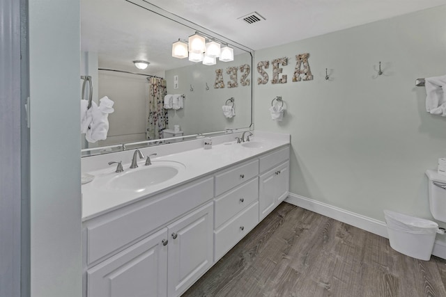 bathroom featuring walk in shower, vanity, wood-type flooring, and toilet