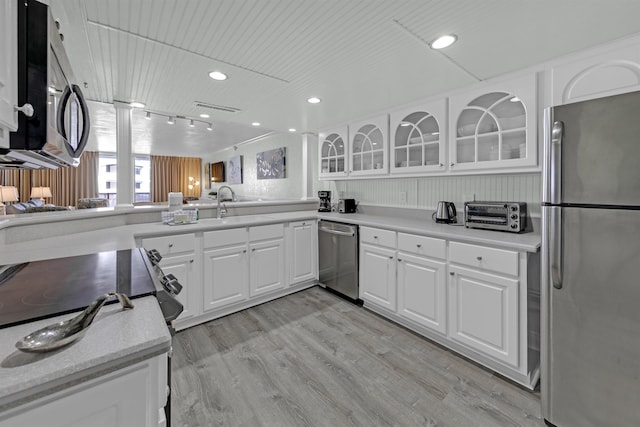 kitchen with light hardwood / wood-style flooring, white cabinets, and appliances with stainless steel finishes