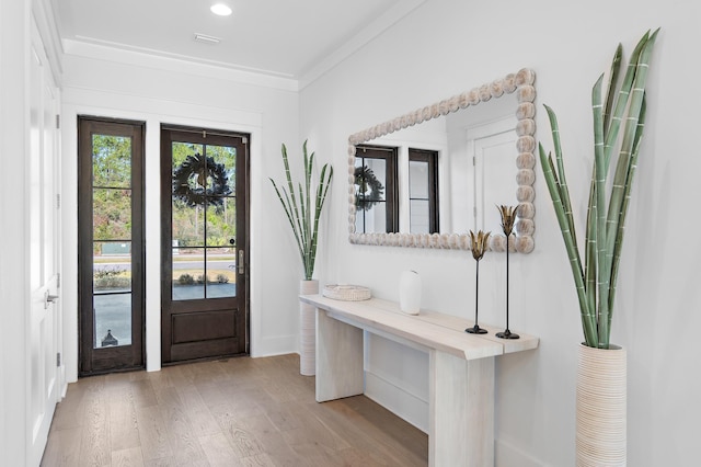 foyer entrance with light wood-type flooring and ornamental molding