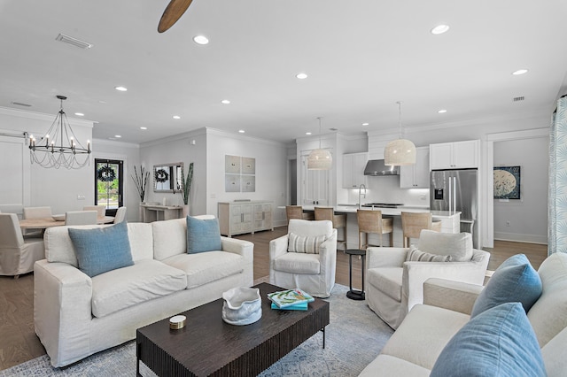 living room with ceiling fan with notable chandelier, sink, light wood-type flooring, and ornamental molding