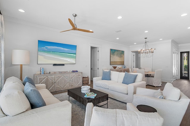 living room featuring hardwood / wood-style floors, ceiling fan with notable chandelier, and ornamental molding