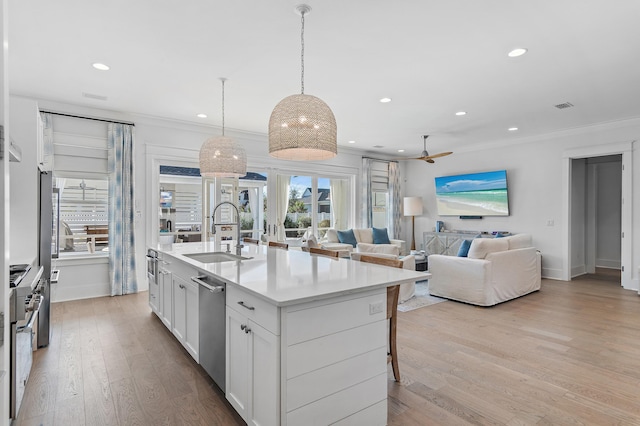 kitchen featuring white cabinets, sink, stainless steel dishwasher, an island with sink, and light hardwood / wood-style floors