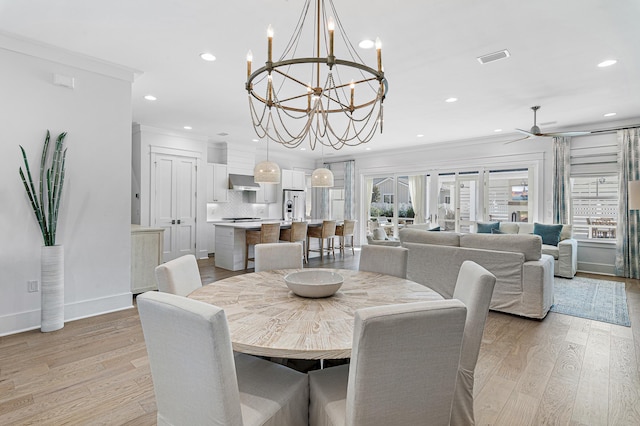 dining space with crown molding, ceiling fan with notable chandelier, and light wood-type flooring